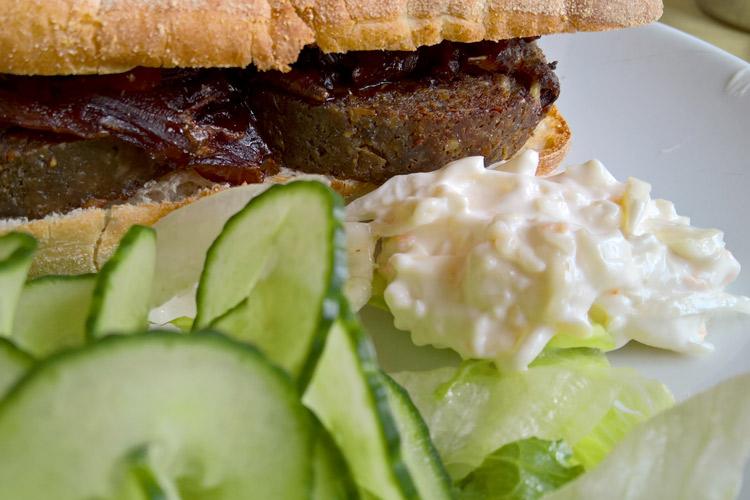 Bocadillo de morcilla con rodajas de pepino y coleslaw.