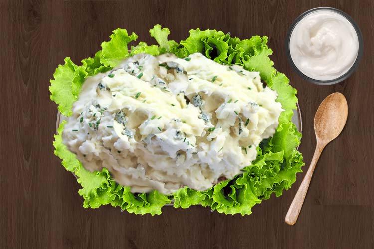 Una ensalada de patata con salsa de queso azul sobre una cama de lechuga.