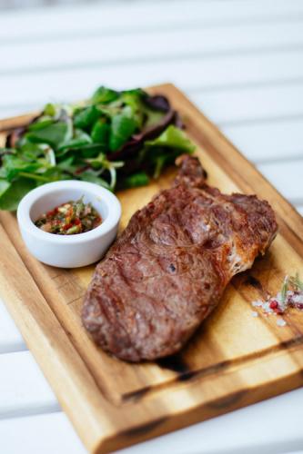 Filete a la plancha sobre tabla de madera con salsa y rúcula.