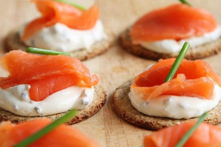 Canapés de salmón ahumado y queso cremoso adornados con cebollino.