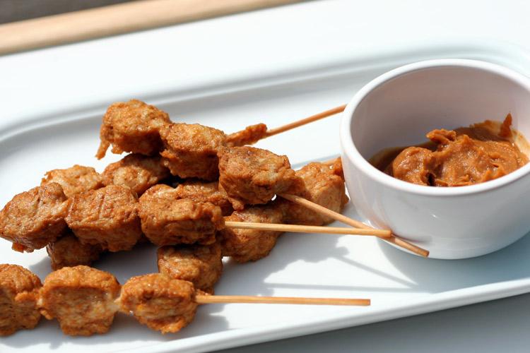 Satays de pollo acompañados de salsa de cacahuetes.