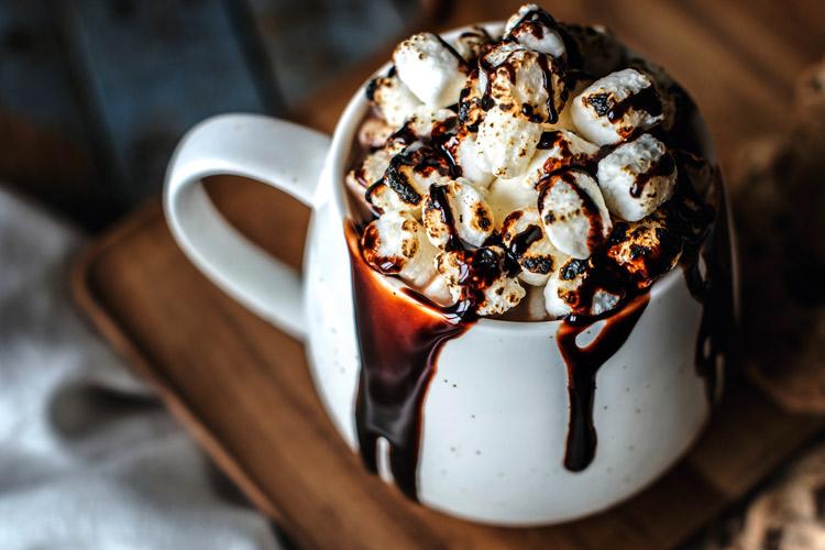 Una taza de chocolate con malvaviscos y jarabe de chocolate.