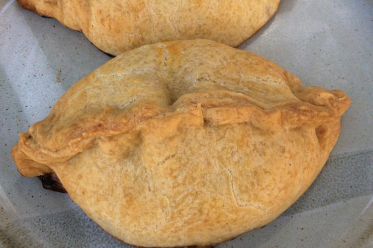 Empanadilla horneada sin pintar con huevo y cerrada en la parte superior.