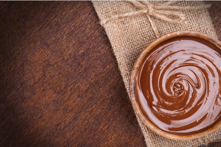 Crema de chocolate en una tarrina individual sobre una servilleta rústica.