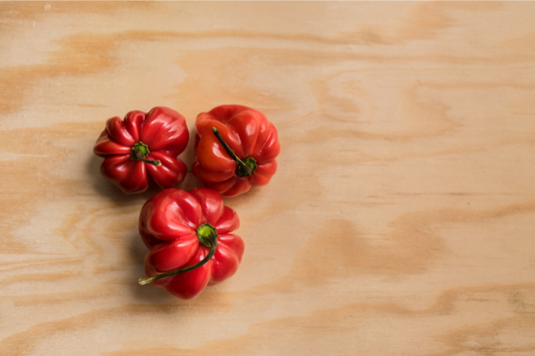 Tres chiles habaneros sobre tabla de madera.