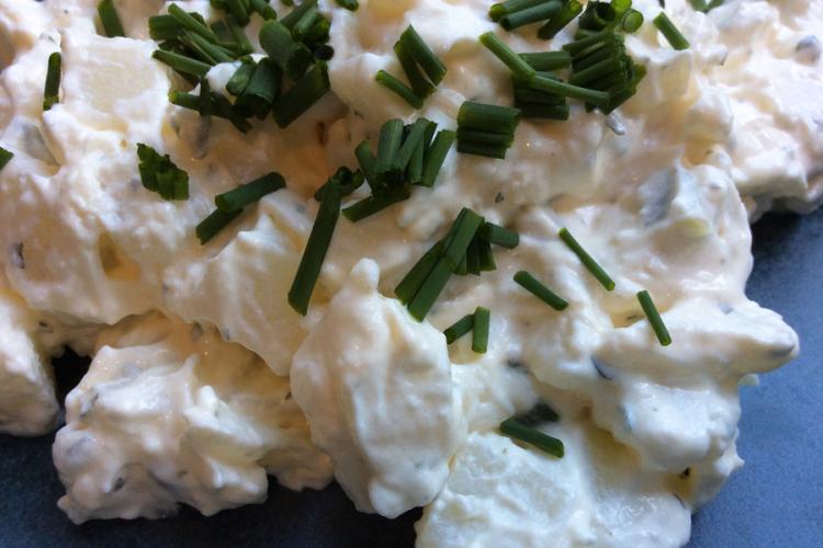 Ensalada de patata al estilo inglés decorada con cebollino picado.