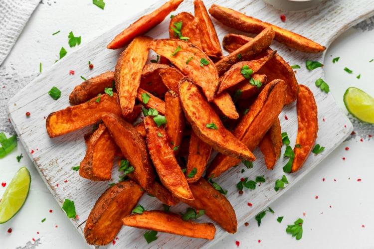 Batatas asadas decoradas con hierbas sobre una tabla blanca.