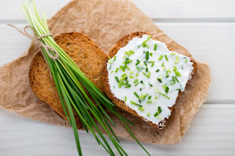 Pan tostado untado con queso crema con cebollino.
