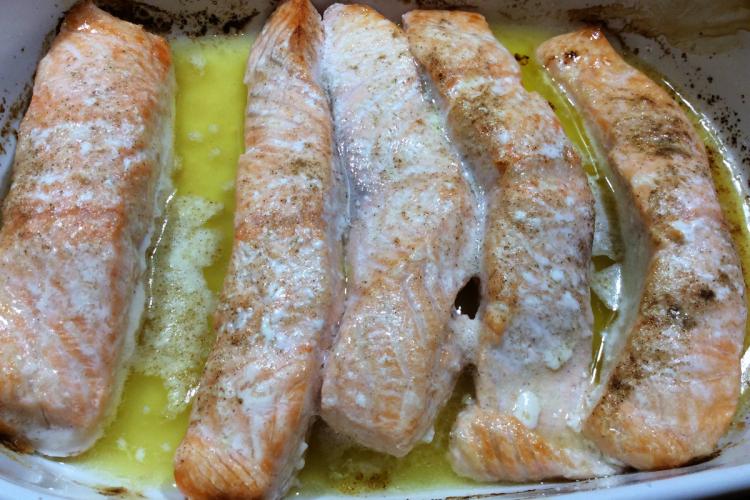 Una fuente con filetes de salmón horneados con mantequilla y limón.