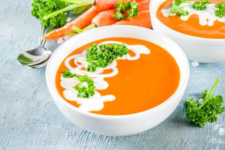 Crema de zanahoria decorada con nata líquida y perejil servida en un cuenco.crema-zanahoria-cv_