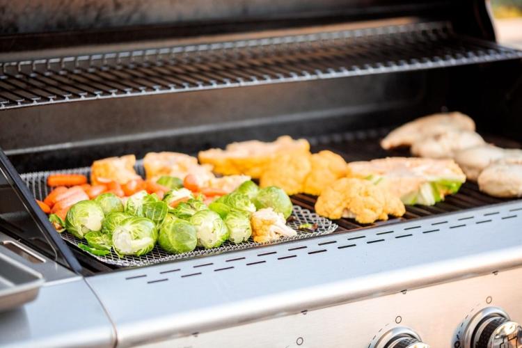 Alimentos cocinándose en una parrilla de gas.