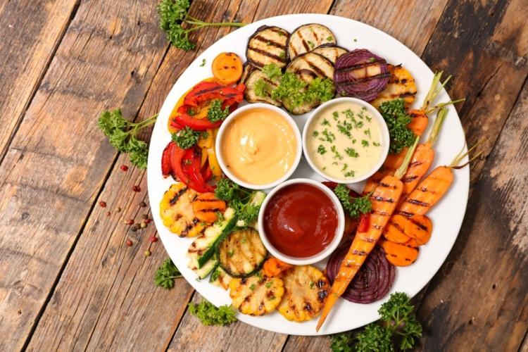 Plato de verduras a la parrilla con varias salsas.