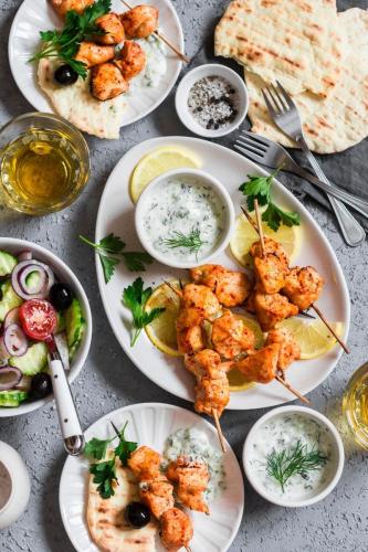 Pinchos de pollo al yogur estilo griego con tzatziki, ensalada y pan pita.