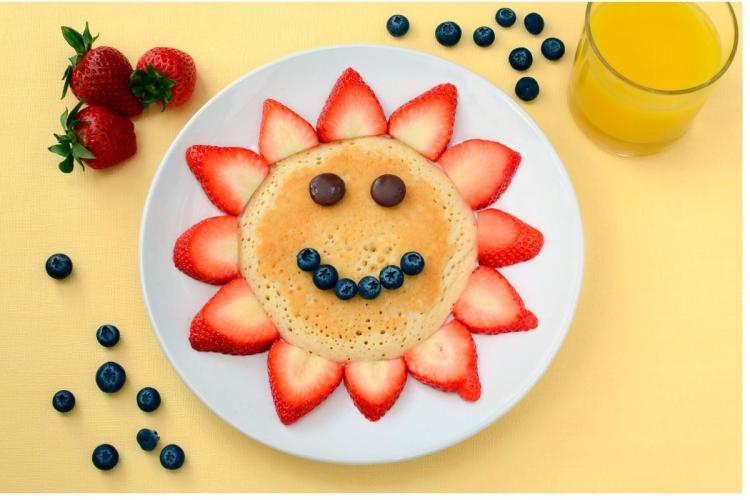 Estrella con carita, con una tortita dulce en el centro y láminas de fresa como rayos.