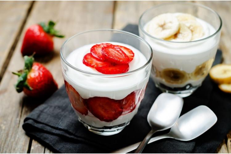 Copas de fruta y yogur, una con fresas y otra con plátano.