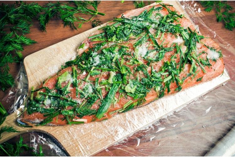 Salmón cubierto de sal, azúcar y eneldo, preparado para convertirse en gravlax.
