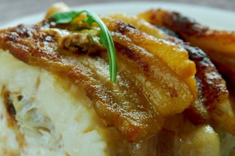 Detalle de bacalao hecho en el horno con tocino ahumado.