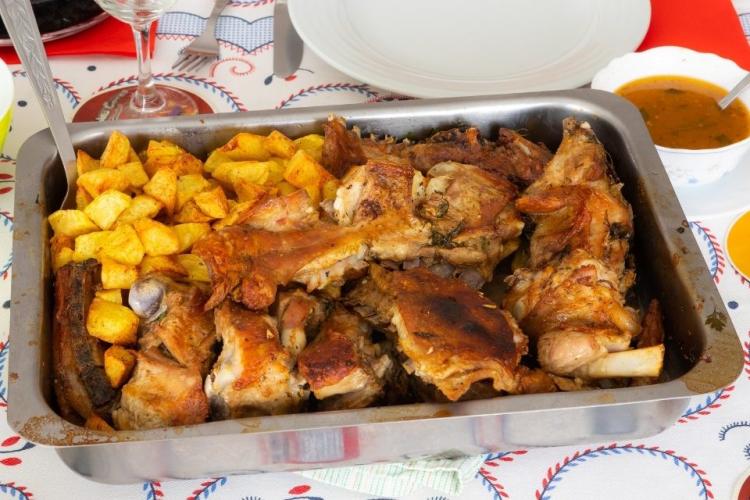 Una fuente con cabrito asado y patatas.