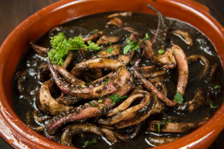 Una cazuela de barro con calamares en su tinta.