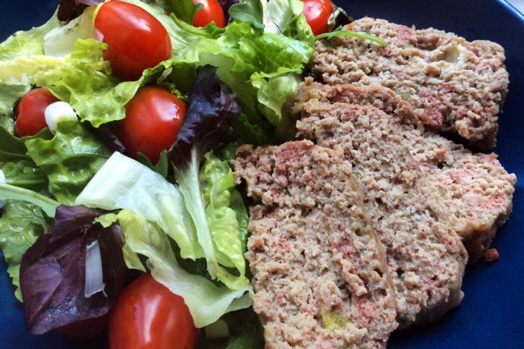 Lonchas de molde de carne fiambre con ensalada en un plato de cerámica azul.
