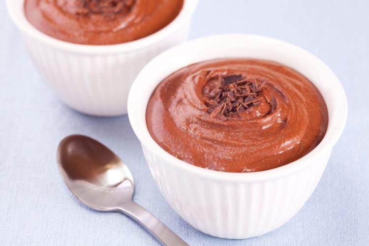 Postre de chocolate en un recipiente blanco con una cuchara al lado.