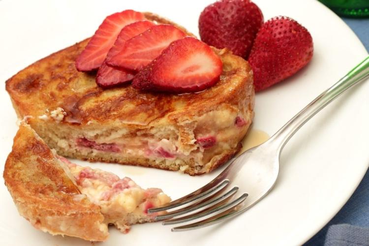 Tostada francesa rellena de fresas y queso en un plato.