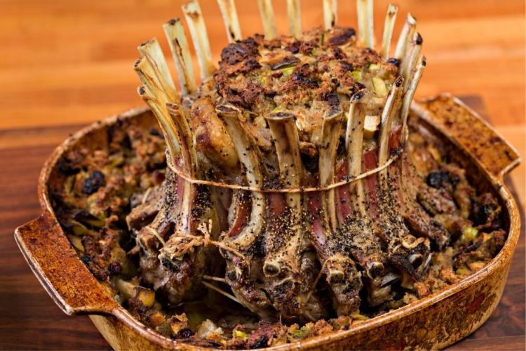 Corona de chuletas rellena recién salida del horno en su fuente refractaria.