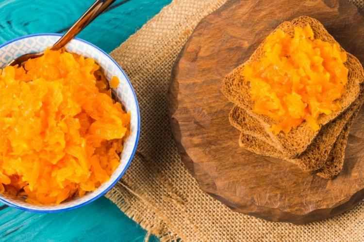 Pan tostado con dulce de zanahoria y un cuenco con dulce de zanahoria.