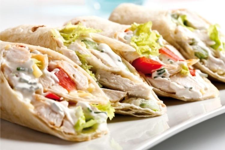 Burritos de pollo y verduras cortados por la mitad en diagonal.