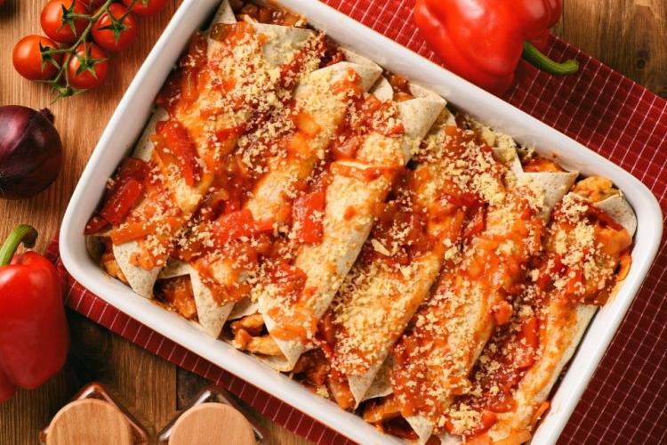 Una fuente de horno con enchiladas de pollo.
