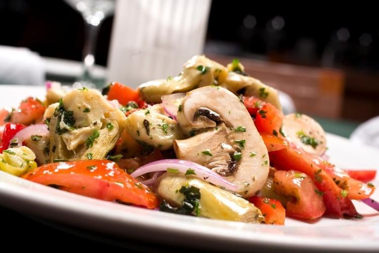Un plato de ensalada de alcachofa, pimiento y champiñones.