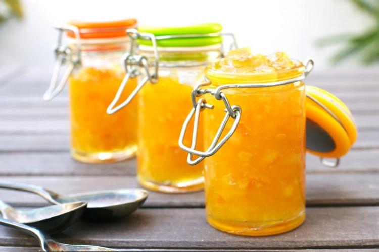 Tres recipientes de vidrio con mermelada de naranja.