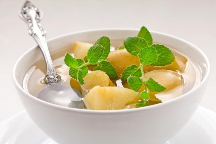 Un cuenco con compota de manzana adornada con hojas de menta.