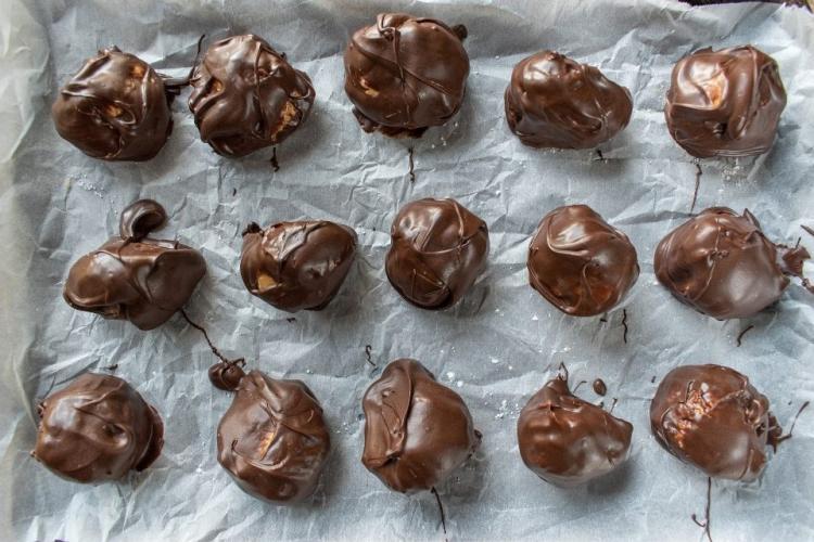 Bolas de mantequilla de cacahuete y chocolate secándose sobre papel parafinado.