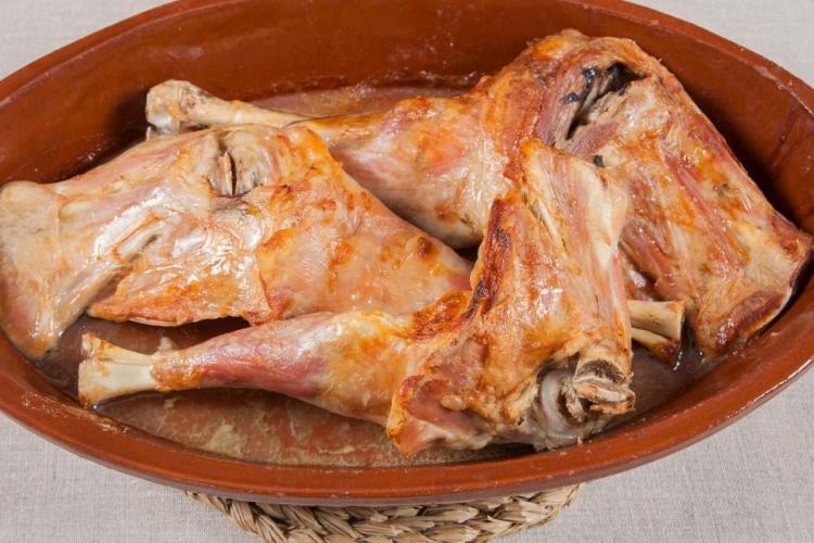 Una fuente de barro con piernas de cordero lecha asadas al estilo español.