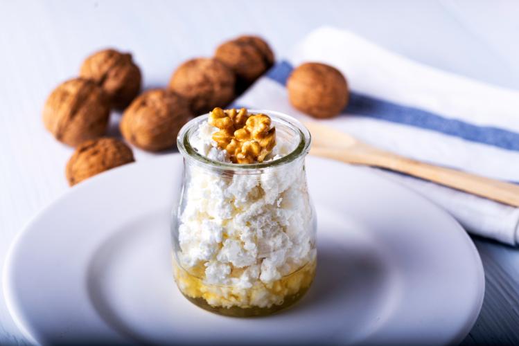 Requesón con miel decorado con nueces en un recipiente de vidrio.