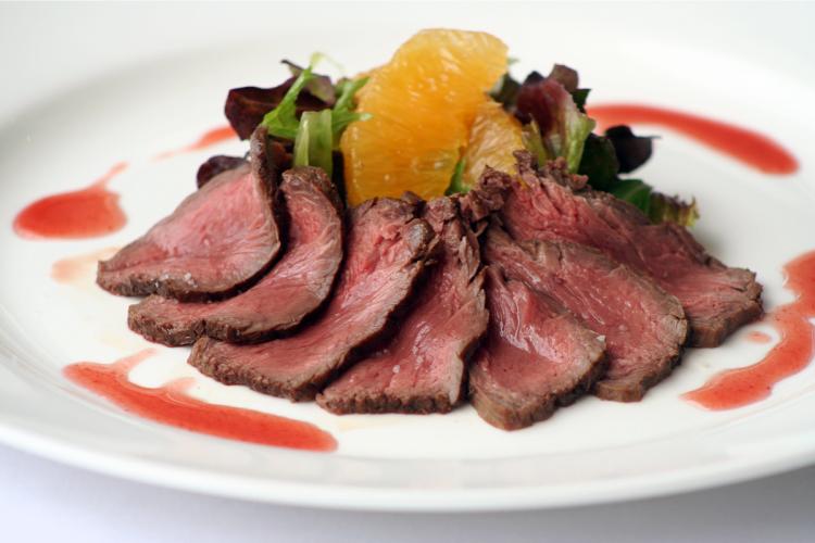 Canguro a la plancha fileteado fino con salsa de frambuesa y ensalada de naranja.