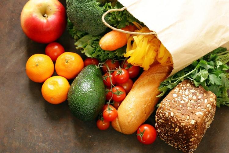 Alimentos saliendo de una bolsa de la compra de papel.