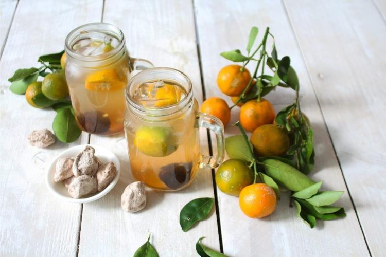 Zumo de lima calamansi, calamansis con hojas y ciruelas secas.
