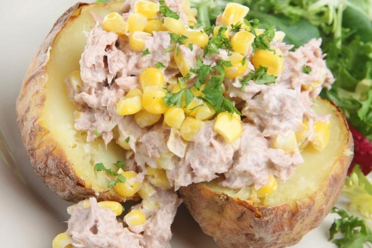 Una patata asada cubierta de atún con mayonesa y maíz tierno.