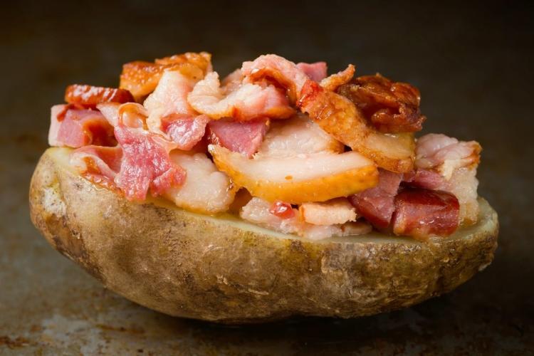 Media patata asada cubierta de beicon frito.