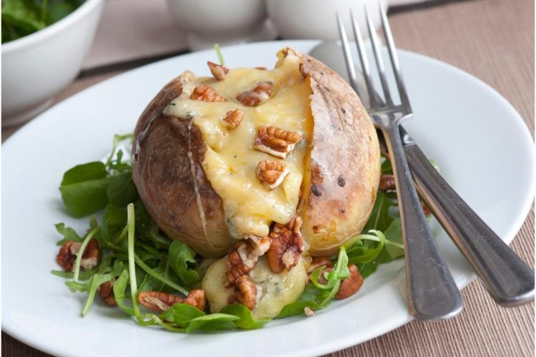 Una patata asada rellena de queso fundido con nueces.