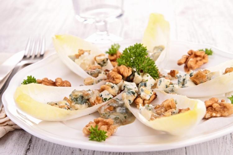 Un plato con ensalada de endibias y nueces con vinagreta al roquefort.