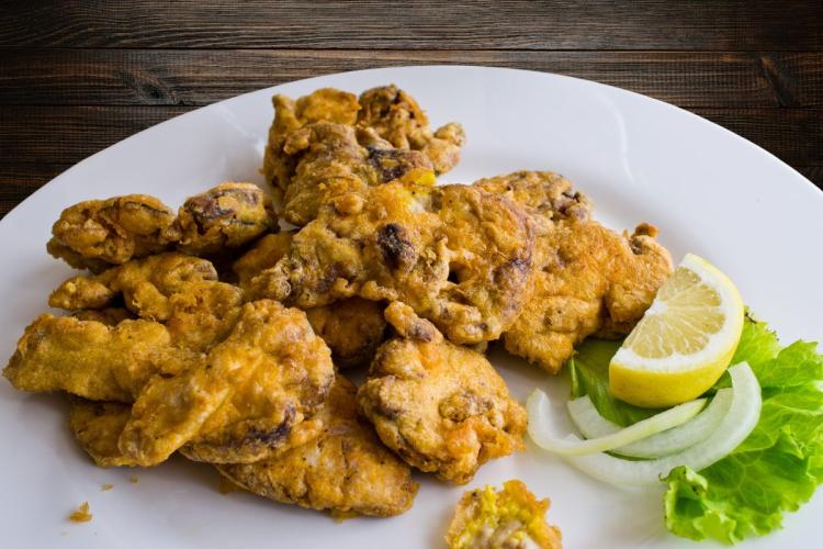 Sesos de cordero rebozados y fritos, acompañados de limón, cebolla y lechuga.