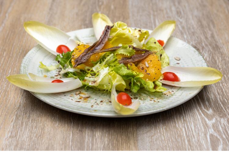 Ensalada de endibias con anchoas, tomate, naranja y lechuga.