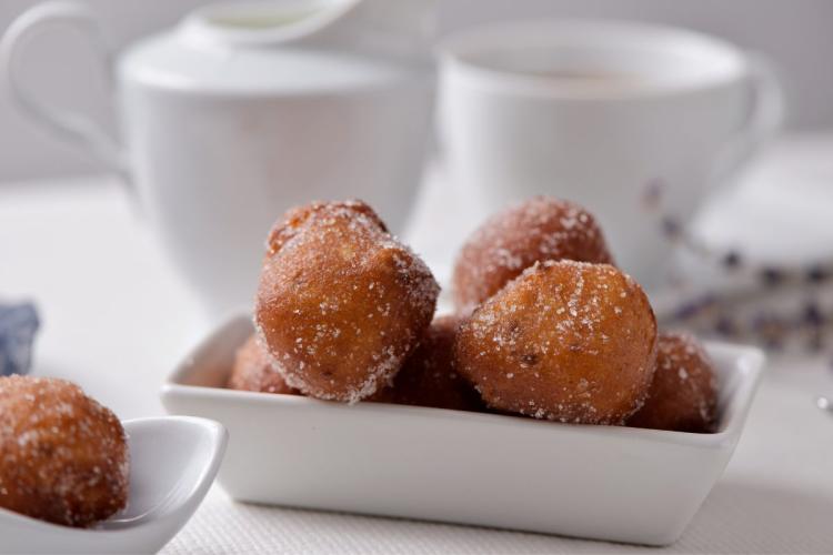 Buñuelos de Cuaresma en una fuente con un servicio de café al fondo.
