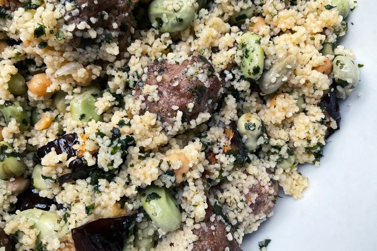 Detalle de una ensalada de cuscús con albóndigas de carne, habas tiernas, garbanzos cocidos y berenjena frita.