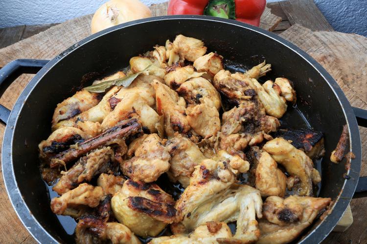 Una cazuela baja con pollo frito con ajo antes de añadir el vino.
