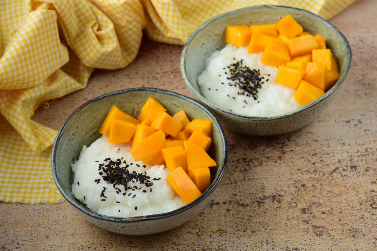 Dos cuencos con arroz con mango tailandés decorado con semillas de sésamo negro tostadas.