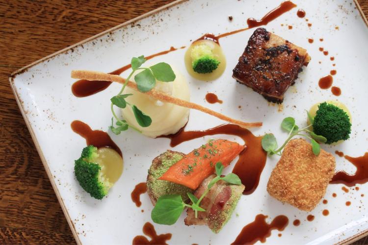 Un plato de carne de cerdo y verduras desconstruido.